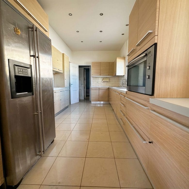Long galley kitchen with wood cabinetry, tiled floor, and built-in appliances, Anaktora, Kolonaki, Athens, Greece