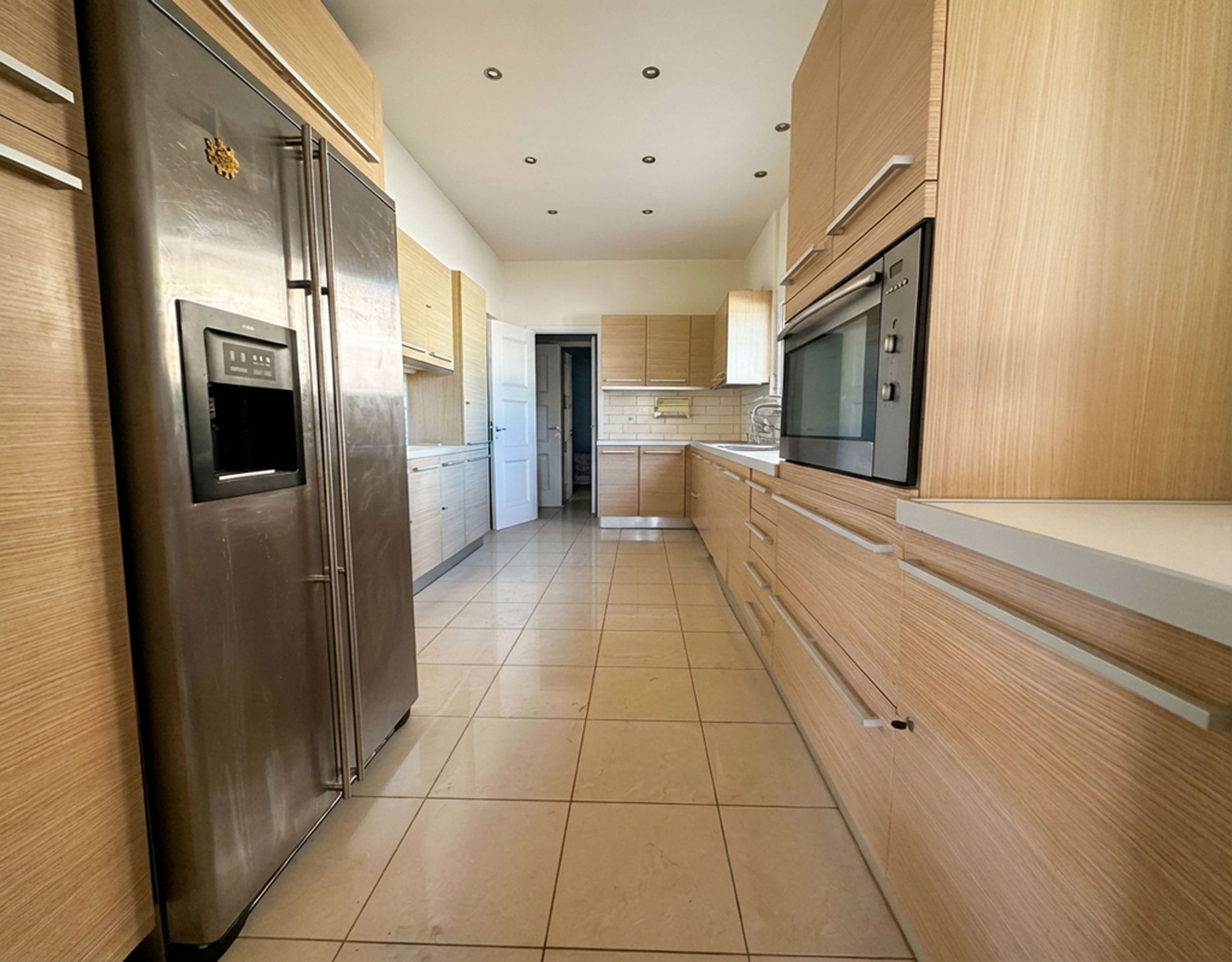 Long galley kitchen with wood cabinetry, tiled floor, and built-in appliances, Anaktora, Kolonaki, Athens, Greece