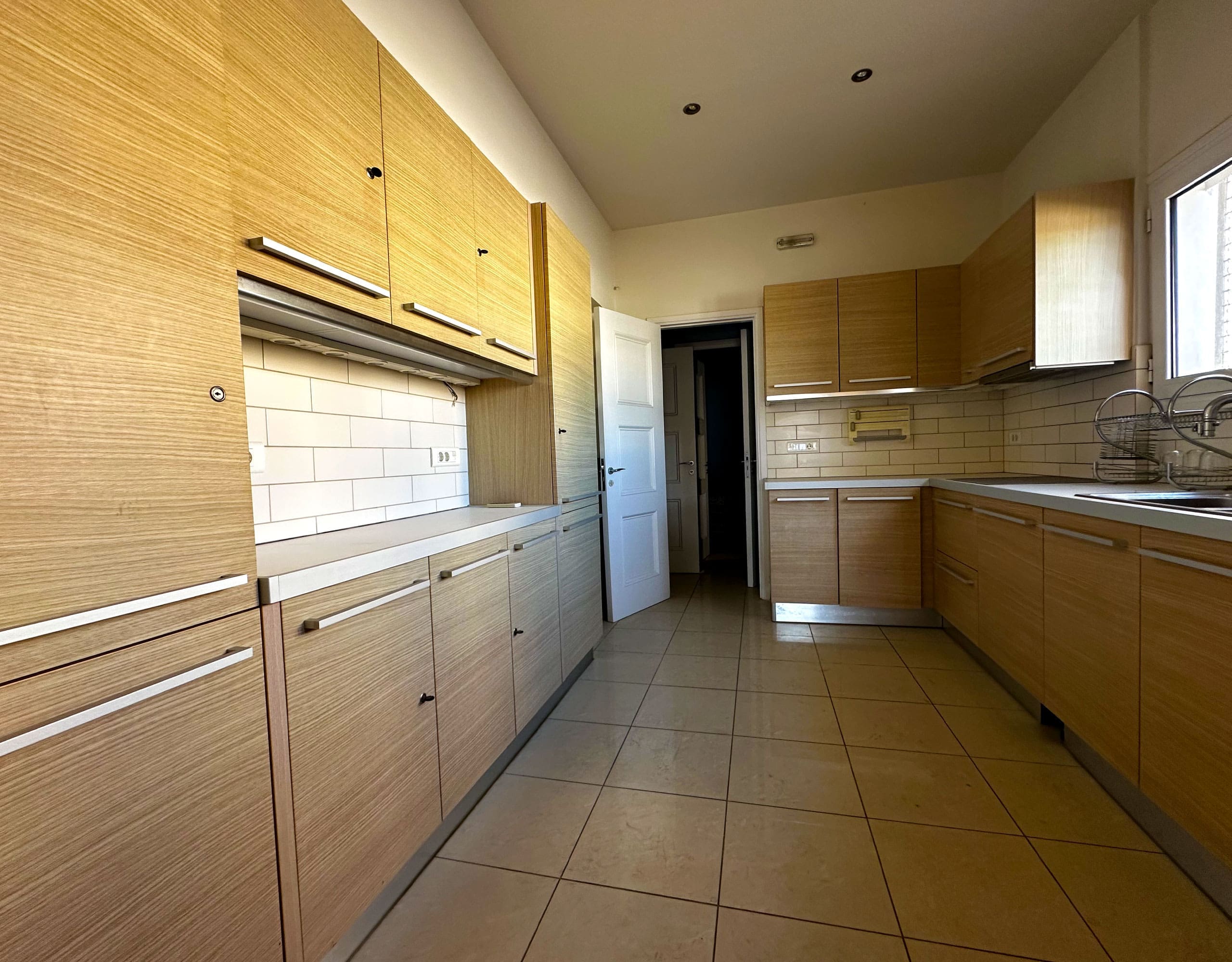 Long kitchen with wood cabinetry, tiled floor, and window for natural light, Anaktora, Kolonaki, Athens, Greece