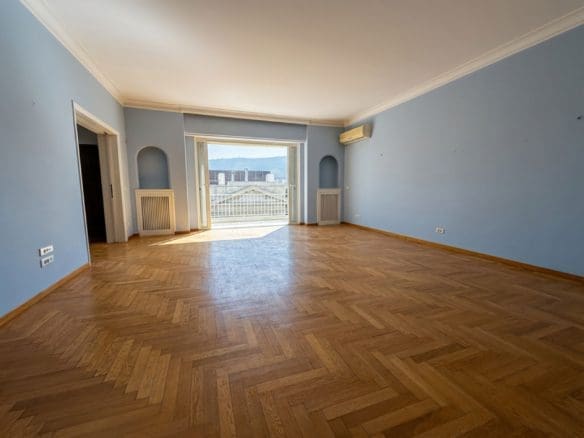 Spacious empty living room with herringbone wood flooring and balcony doors, Anaktora, Kolonaki, Athens, Greece