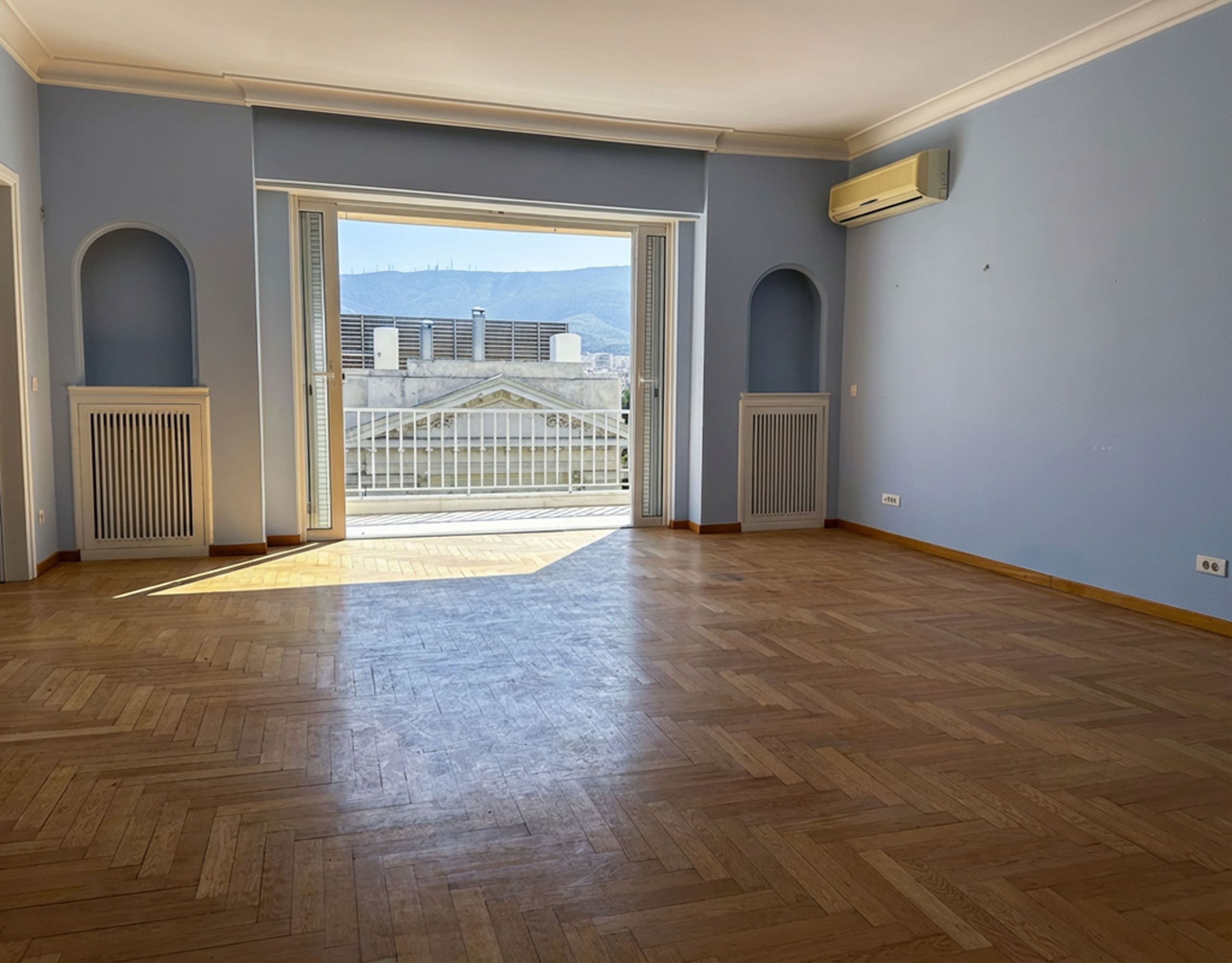 Bright living room with wood flooring and large balcony doors with city views, Anaktora, Kolonaki, Athens, Greece