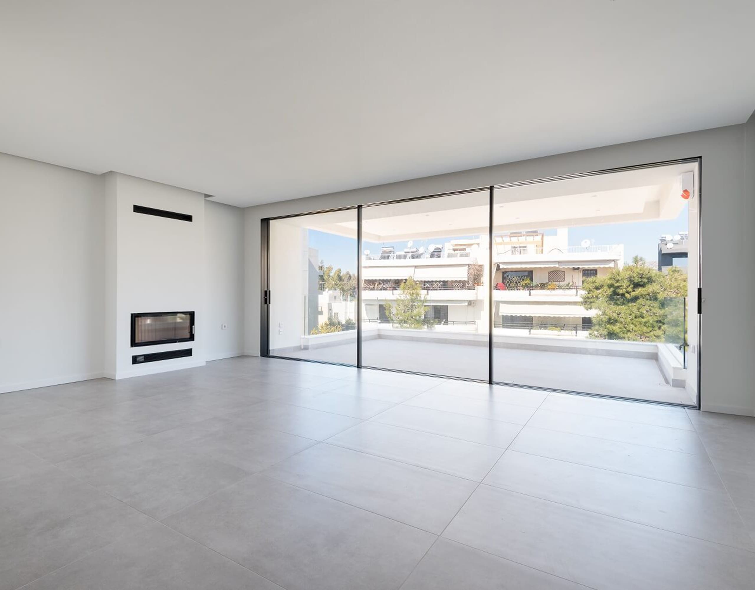 Bright open-plan living area with large sliding doors and built-in fireplace niche, Athens Riviera, Greece