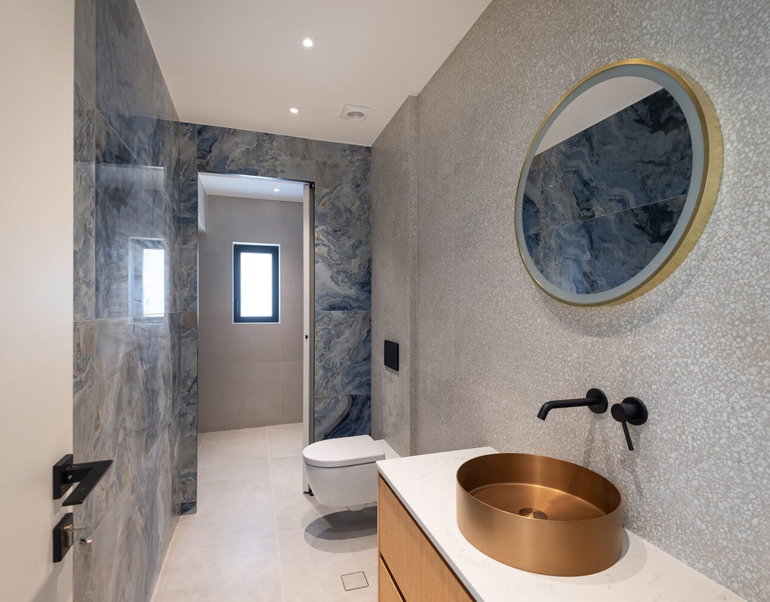 Modern bathroom with round mirror, stone-textured walls, and wall-mounted basin, Athens Riviera, Greece