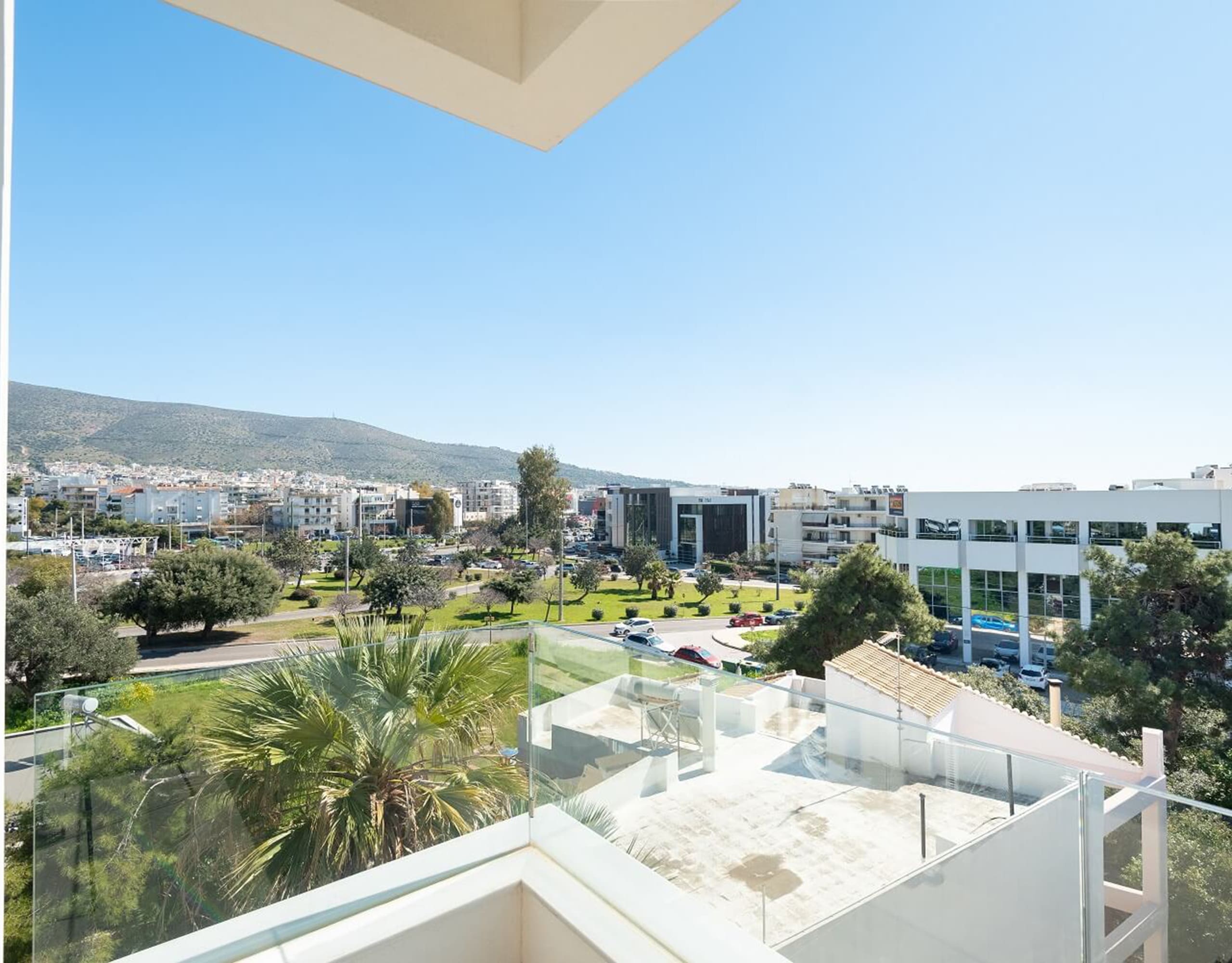 Balcony view over modern neighborhood with greenery and distant hills, Athens Riviera, Greece