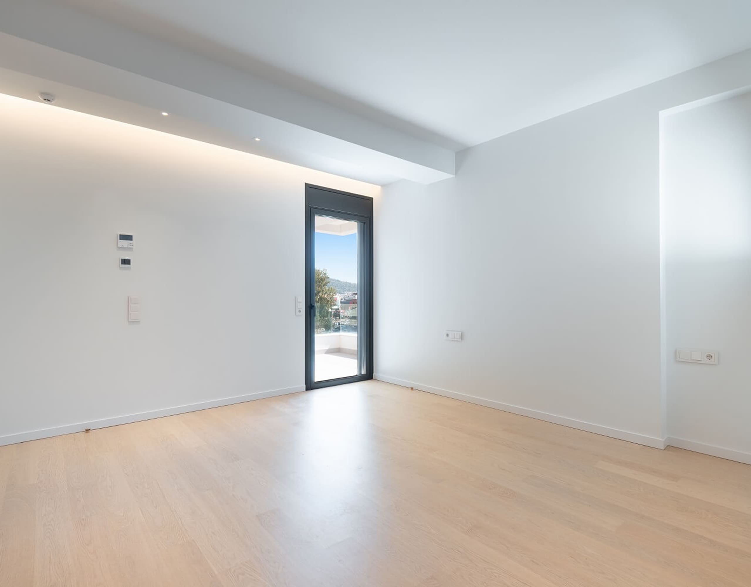 Minimal bright room with wood flooring and balcony door, Athens Riviera, Greece