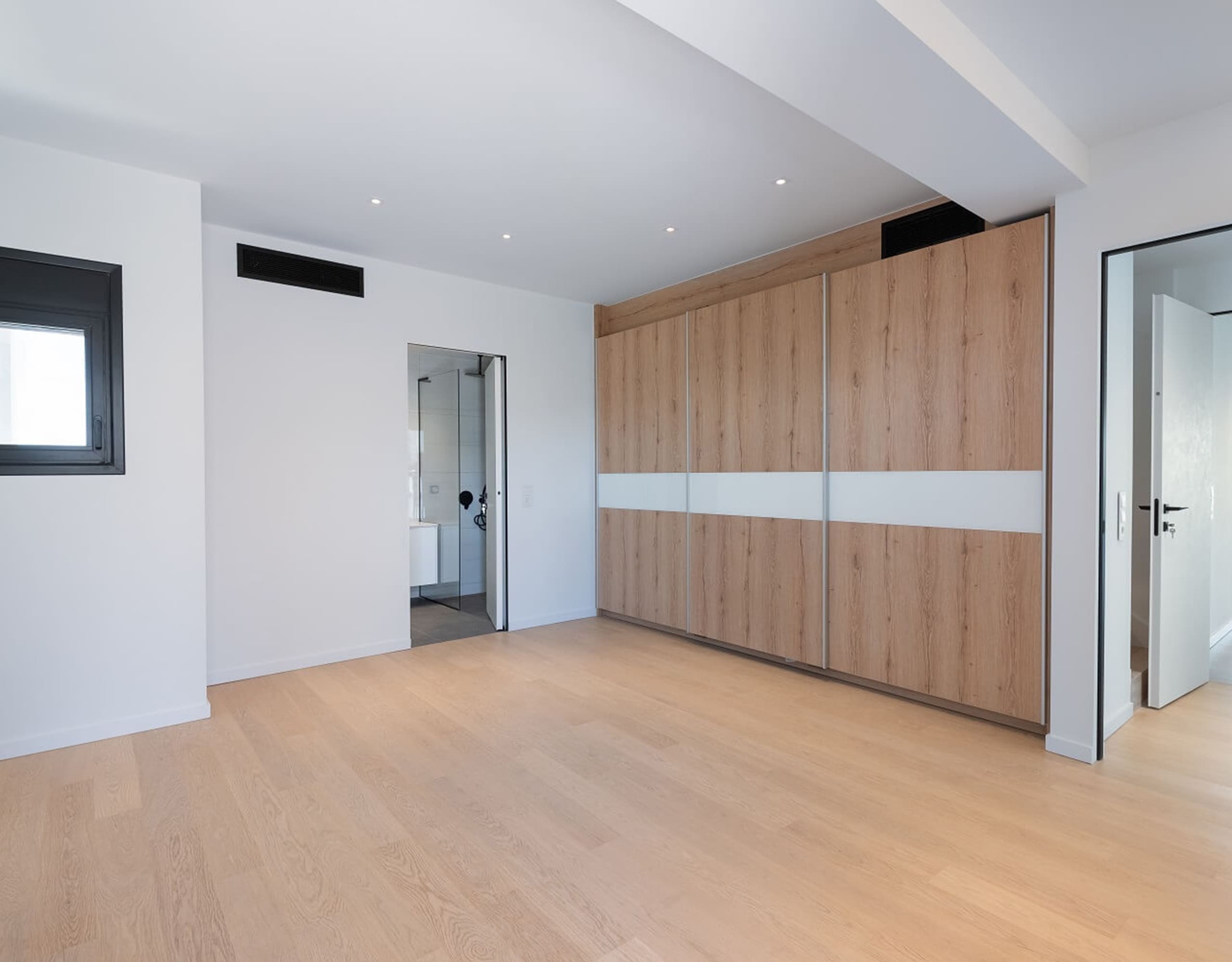 Modern room with built-in wood wardrobe wall and doorway to hall, Athens Riviera, Greece