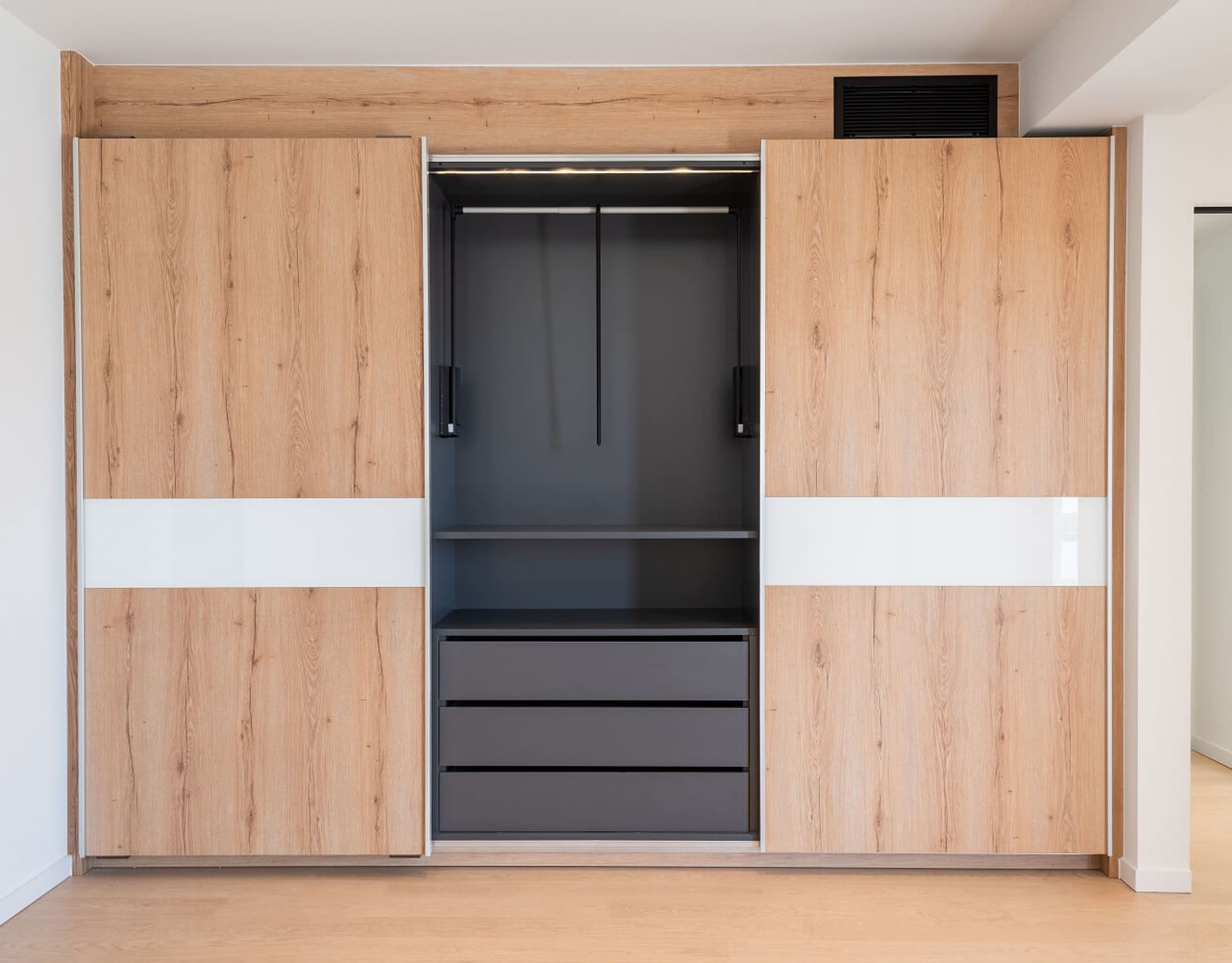 Built-in wood wardrobe wall with integrated storage and a central dark panel, Athens Riviera, Greece