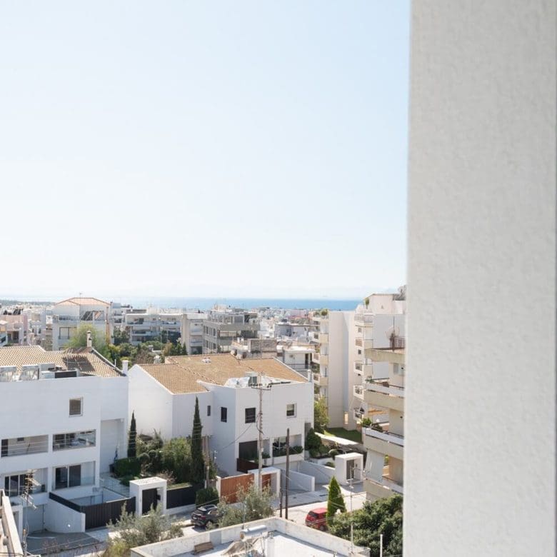 View through a window toward rooftops and distant sea horizon, Athens Riviera, Greece