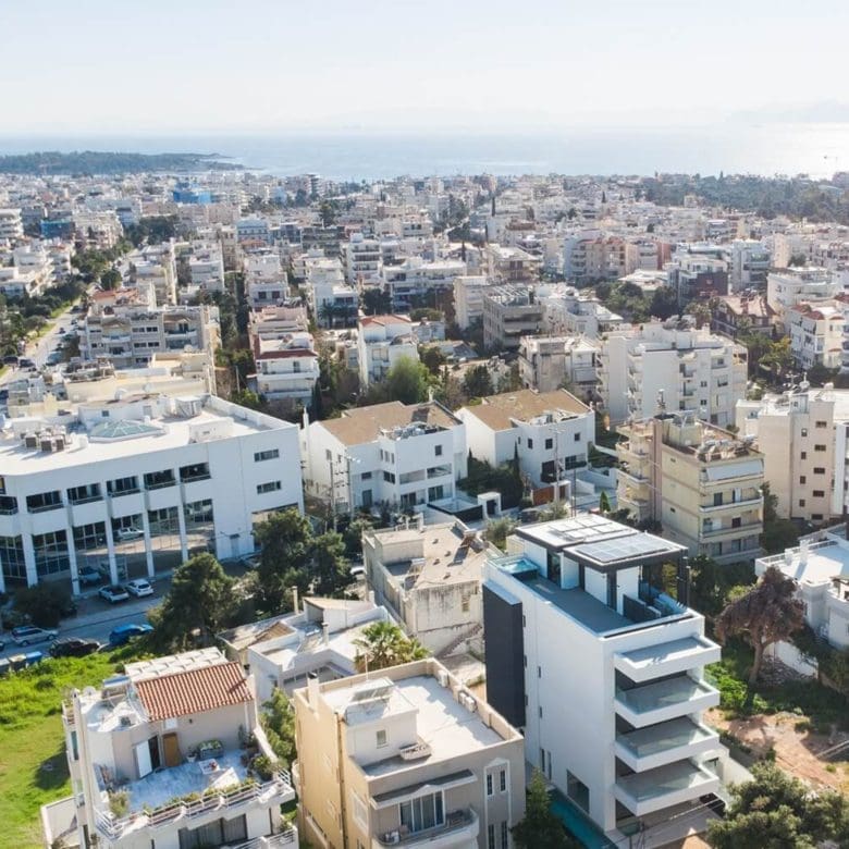 Wide drone view over the neighborhood with the modern villa in the foreground, Athens Riviera, Greece