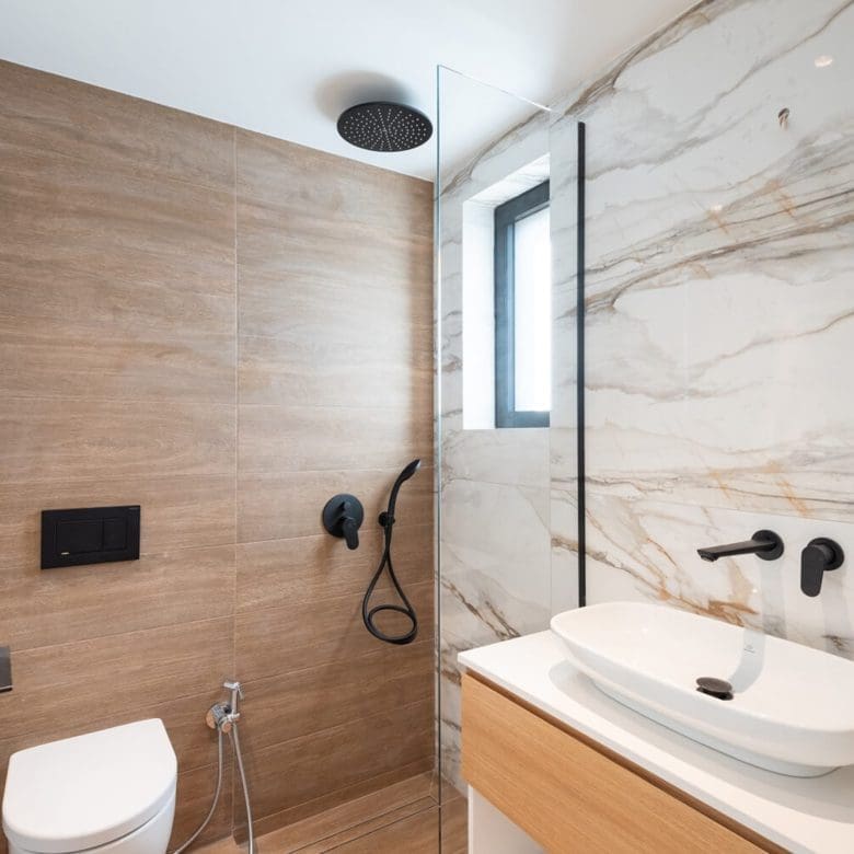 Modern bathroom with wood vanity, marble-look wall, and black fixtures, Athens Riviera, Greece