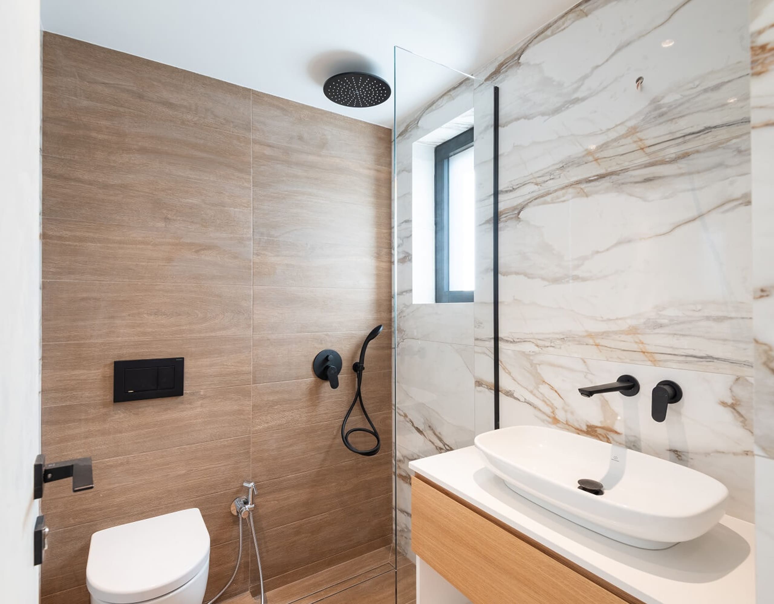 Modern bathroom with wood vanity, marble-look wall, and black fixtures, Athens Riviera, Greece