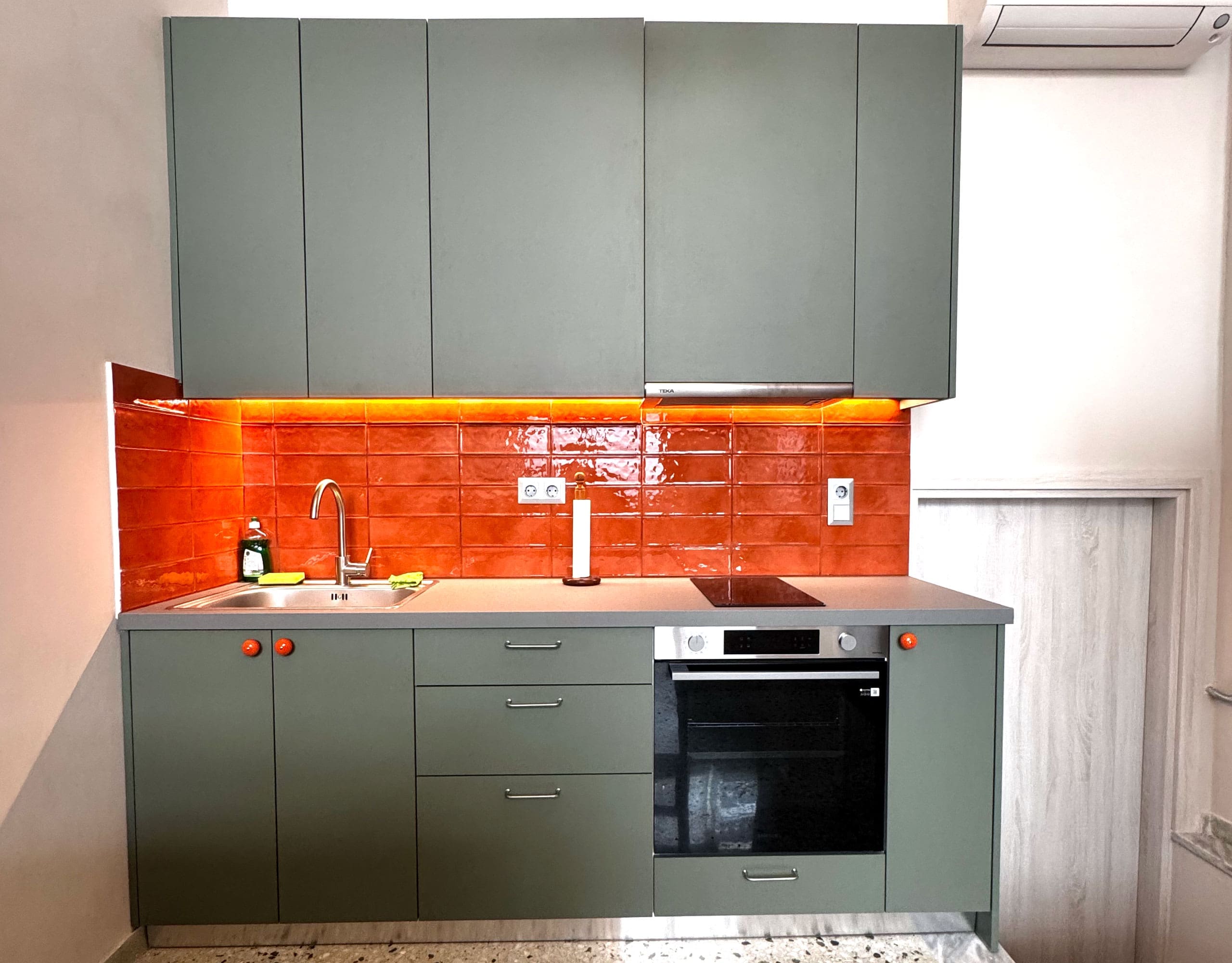 Pangrati Investment Apartment 51 sqm – Compact Kitchen View Compact kitchen with green upper cabinets and orange backsplash, Pangrati, Athens, Greece