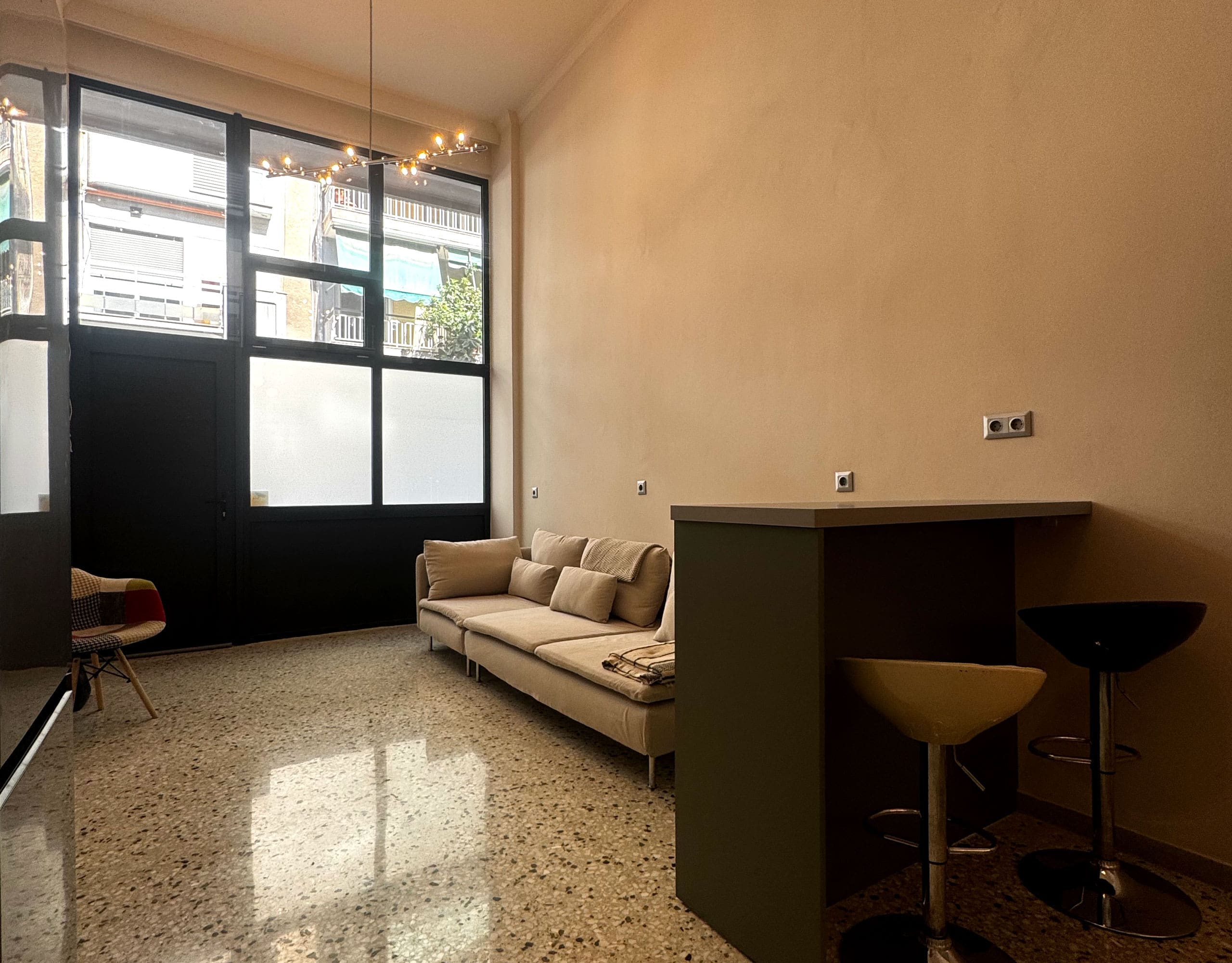 Pangrati Investment Apartment 51 sqm – Living Area With Bar Counter Open-plan living area with large window, bar counter seating, and compact layout, Pangrati, Athens, Greece