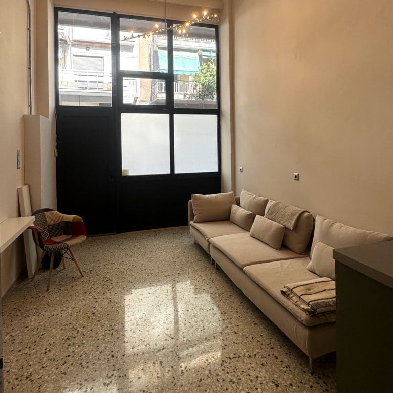 Living room with sofa and large window bringing in natural light, Pangrati, Athens, Greece