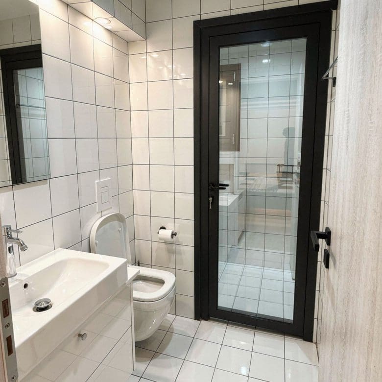 Bathroom with white tiles, vanity, and glass shower door, Pangrati, Athens, Greece