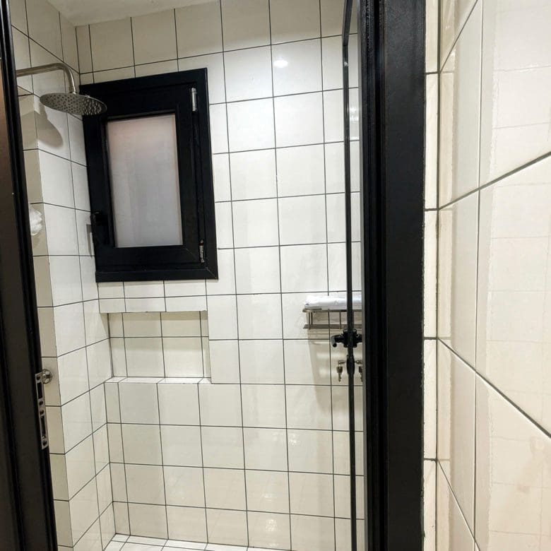 Shower area with white tiled walls and black-framed glass door, Pangrati, Athens, Greece