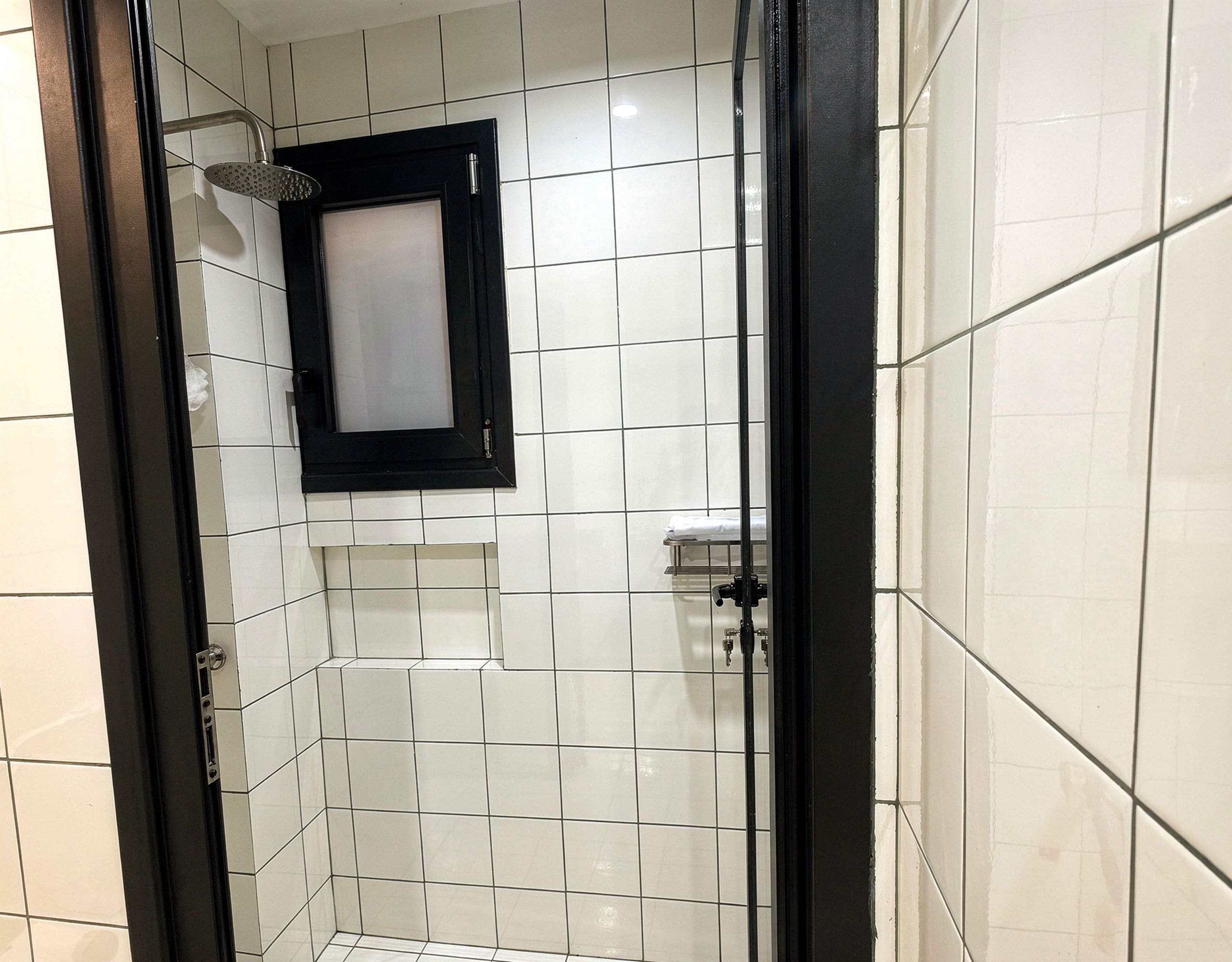 Pangrati Investment Apartment 51 sqm – Shower Detail Shower area with white tiled walls and black-framed glass door, Pangrati, Athens, Greece