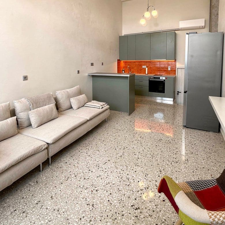 Open-plan living room with sofa and kitchen area in the background, Pangrati, Athens, Greece