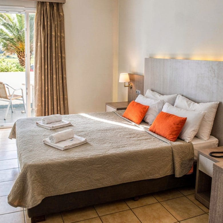 Guest bedroom with double bed, orange accent pillows, and balcony access, Skala Kallonis, Lesvos, Greece