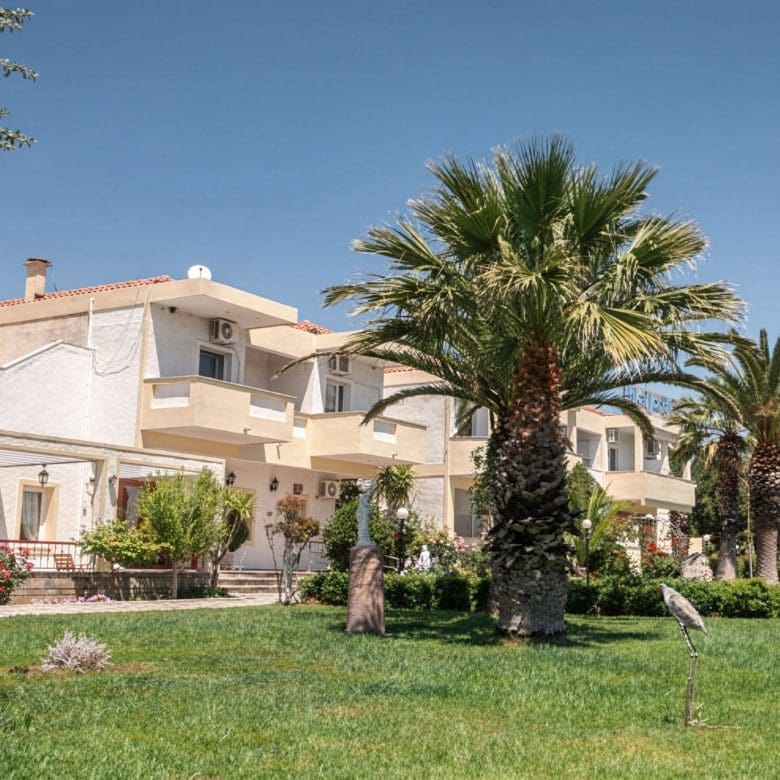 Hotel garden with palm tree, lawn, and building exterior, Skala Kallonis, Lesvos, Greece