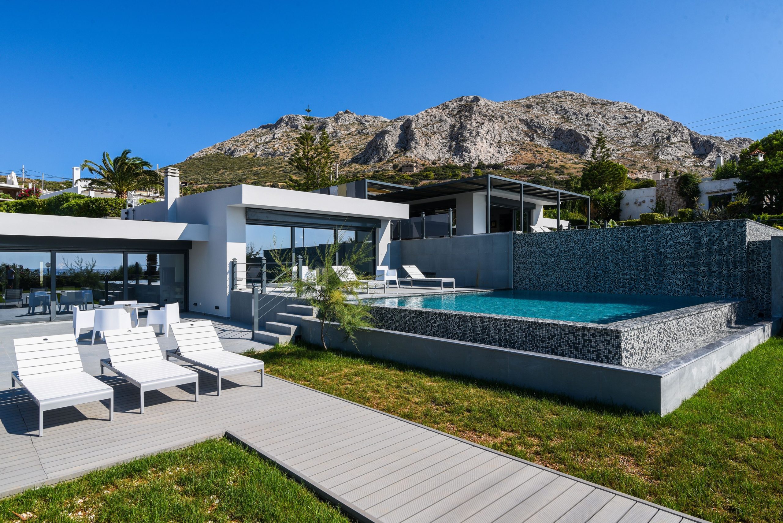 Sounio Beachfront Twin Villas – Exterior And Garden View Modern villa exterior with garden lawn and mountain backdrop, Sounio, Athens Riviera, Greece