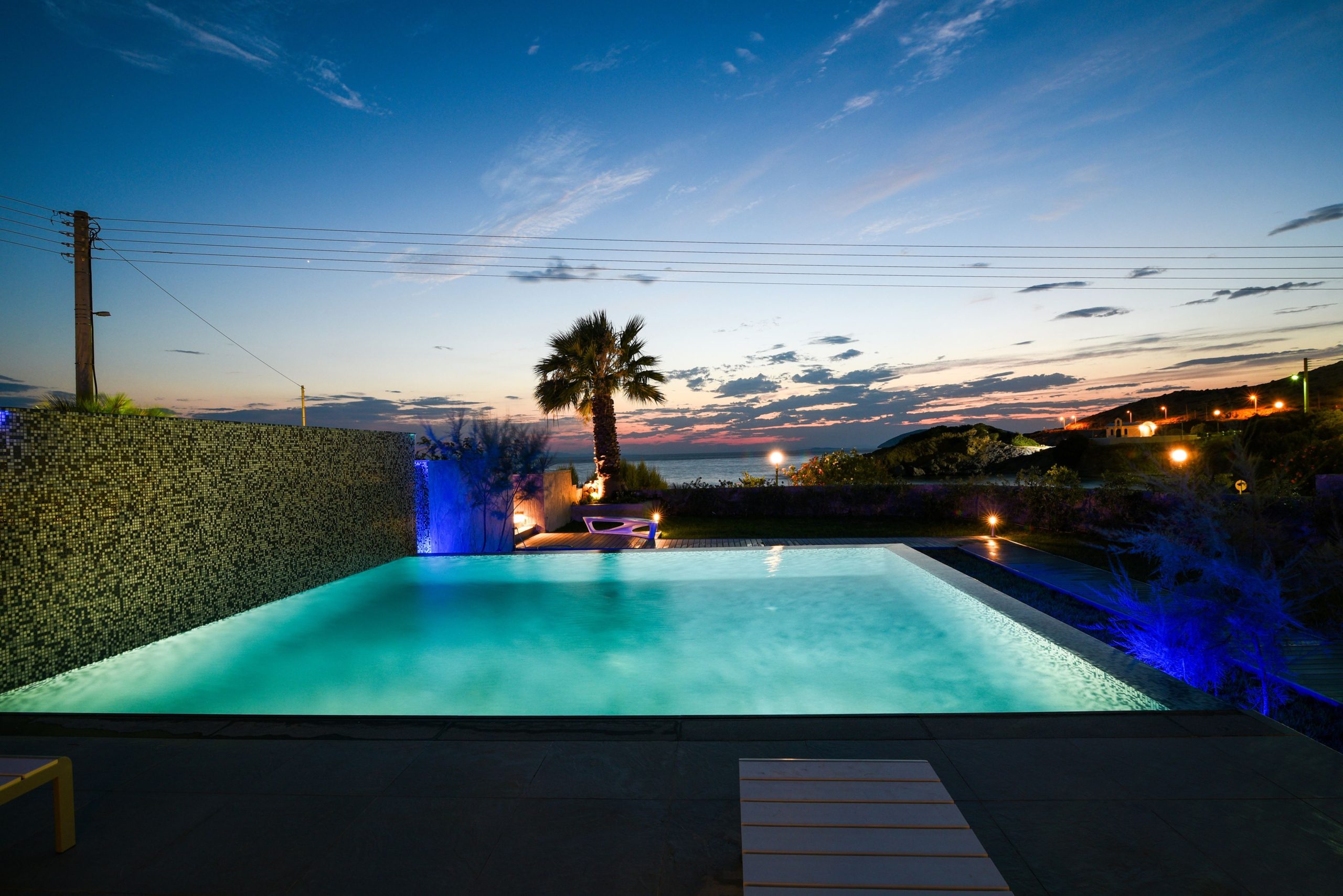 Sounio Beachfront Twin Villas – Dusk Infinity Pool View Infinity pool at dusk with palm silhouettes and open horizon view, Sounio, Athens Riviera, Greece