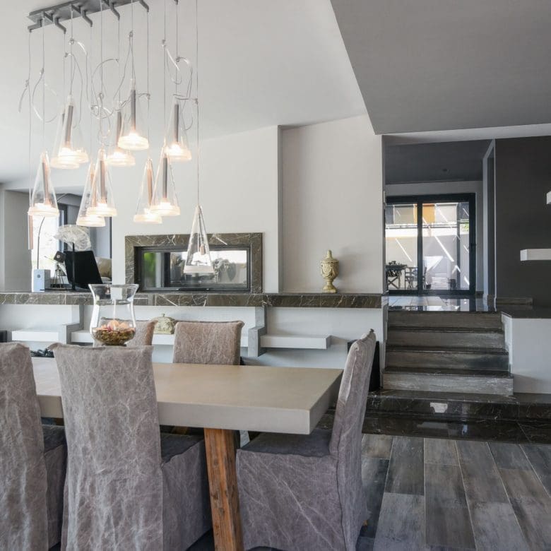 Open-plan dining area with pendant lights and modern kitchen in the background, Sounio, Athens Riviera, Greece