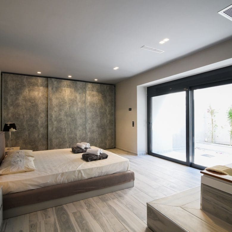 Modern bedroom with double bed and large sliding doors to the balcony, Sounio, Athens Riviera, Greece