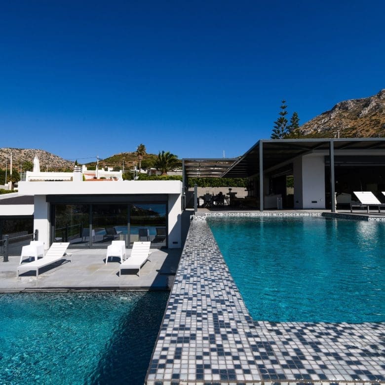 Infinity pool view with sun loungers and modern villa volumes, Sounio, Athens Riviera, Greece