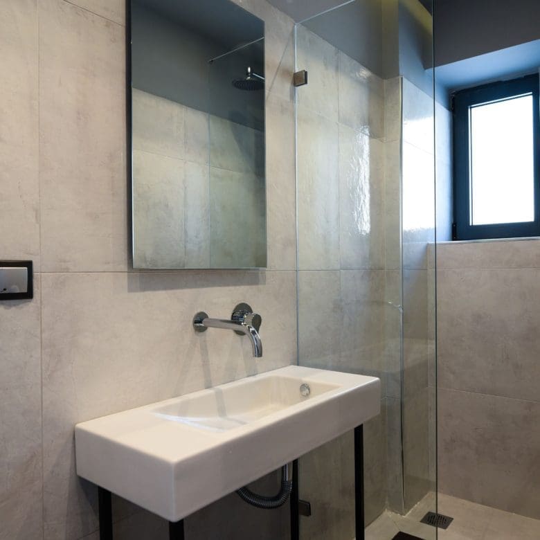 Minimal bathroom with wall-mounted sink, walk-in shower, and window, Sounio, Athens Riviera, Greece