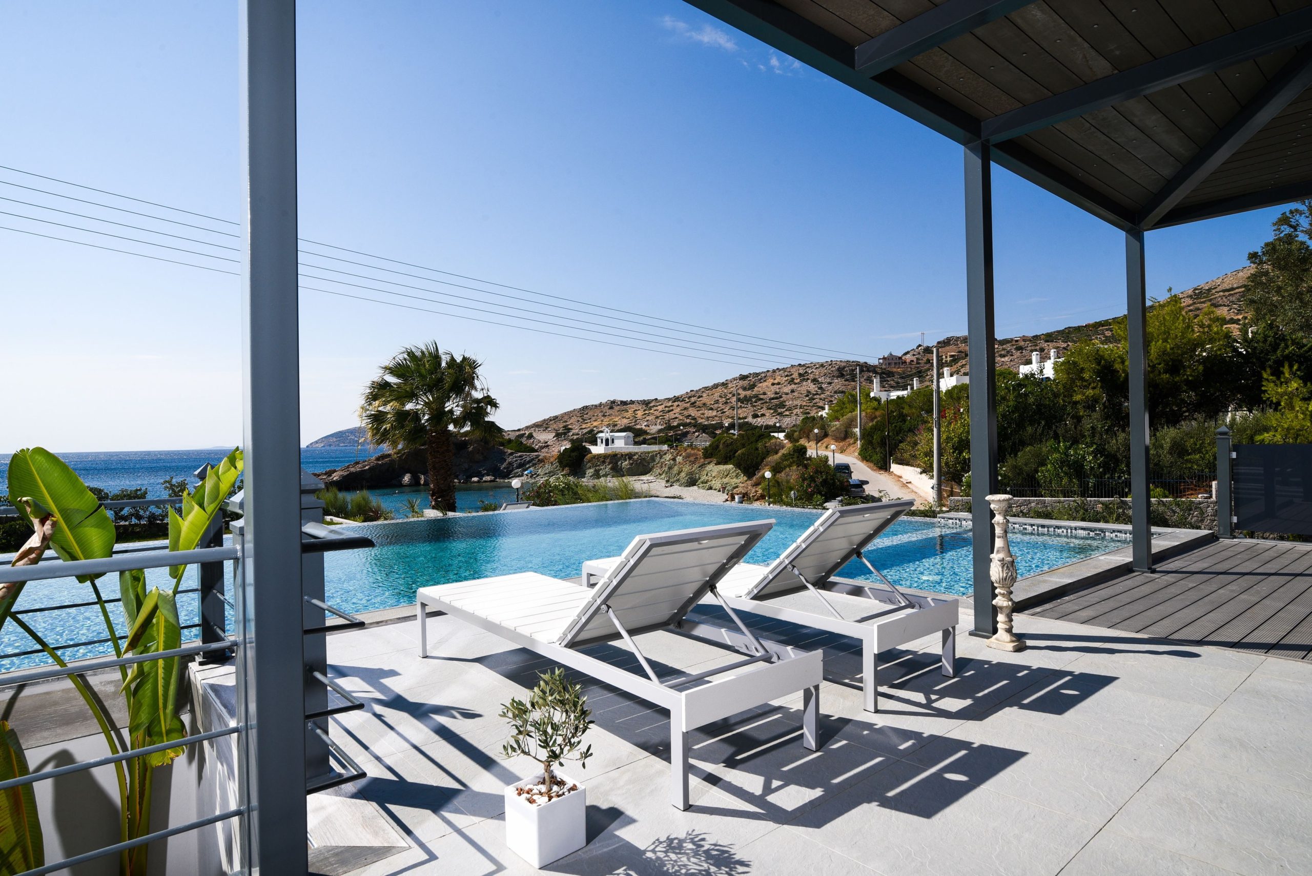 Sounio Beachfront Twin Villas – Poolside Pergola Lounge Poolside terrace with sun loungers under a pergola and sea-view setting, Sounio, Athens Riviera, Greece