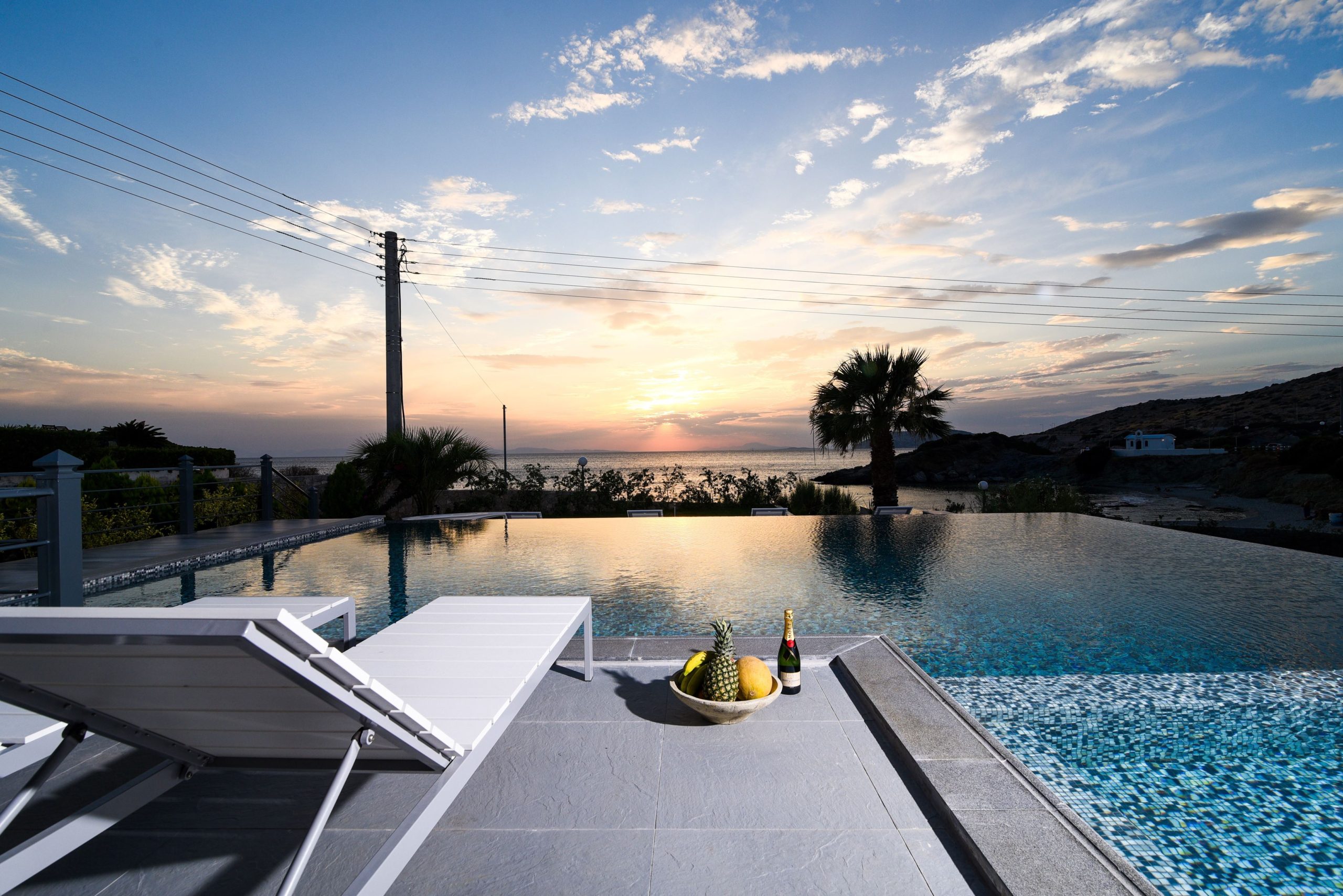 Sounio Beachfront Twin Villas – Sunset Pool View Infinity pool at sunset with loungers and open horizon views, Sounio, Athens Riviera, Greece