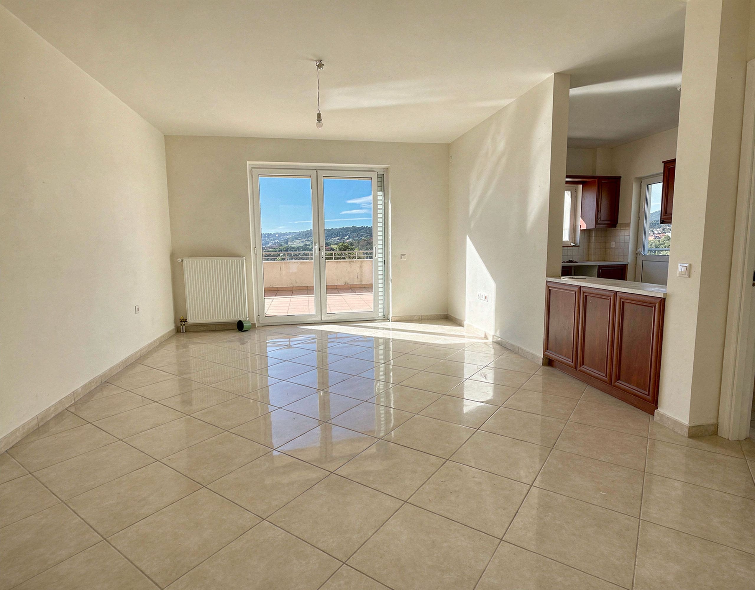 Bright open-plan living area with tiled floor and balcony doors, Vasiliko, Evia, Greece