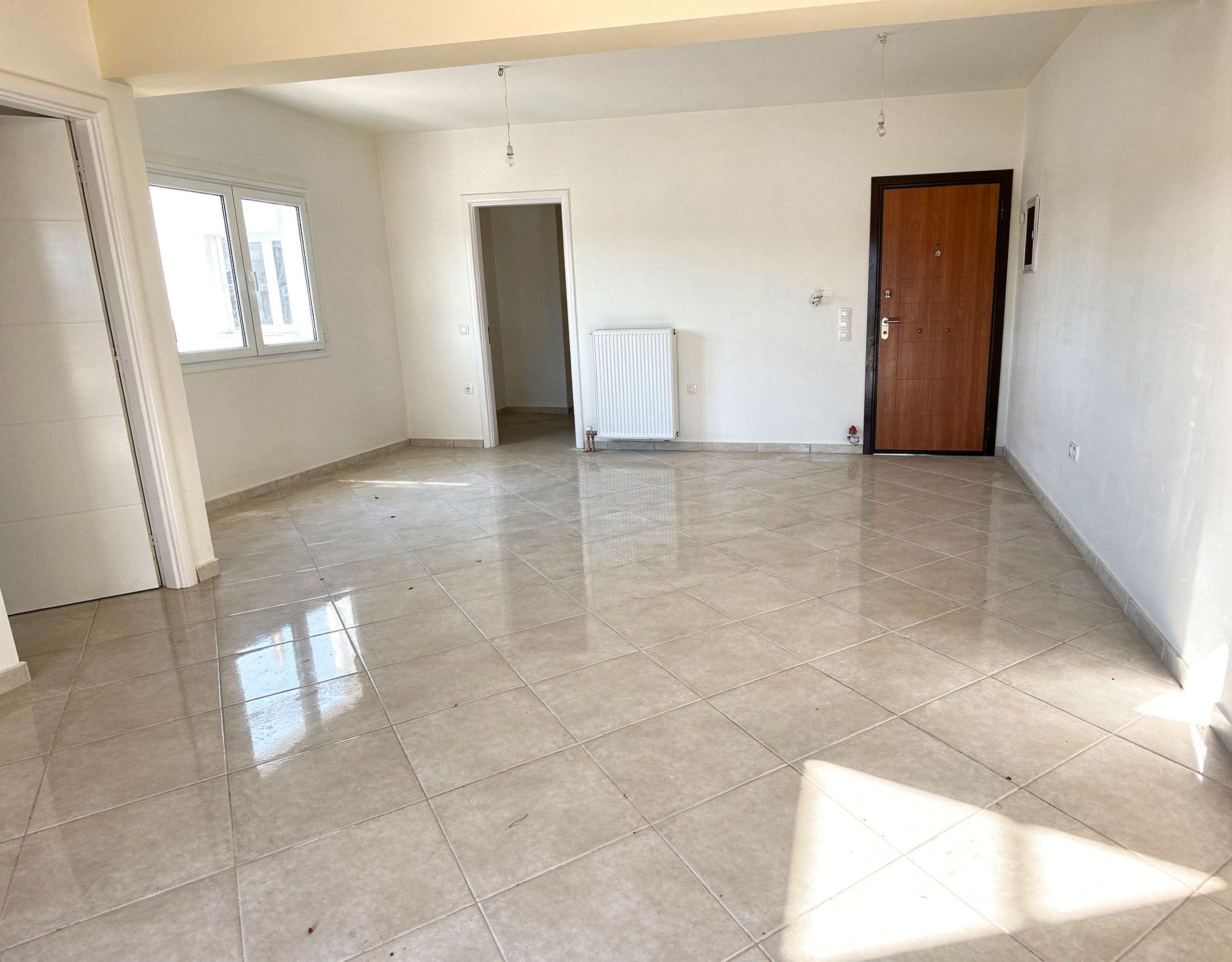 Spacious empty living room with tiled floor and entry door, Vasiliko, Evia, Greece
