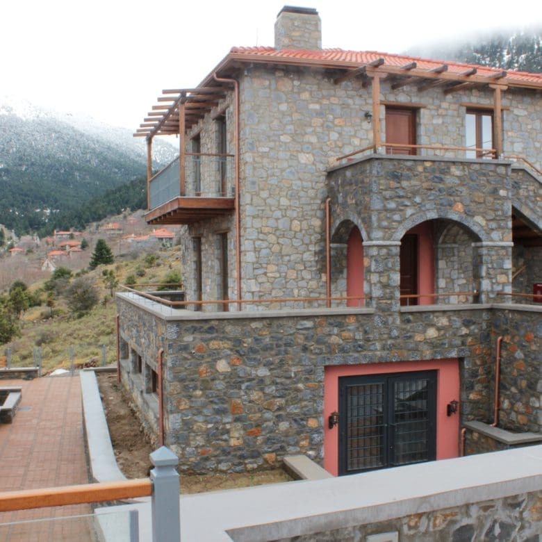 Stone-built hotel facade with arched balcony and mountain backdrop, Kardaras, Mount Mainalo, Arcadia, Greece
