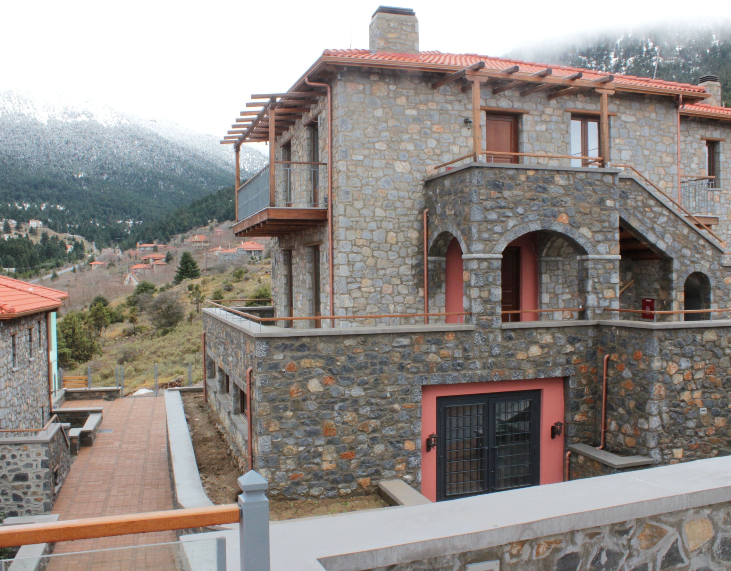 Stone-built hotel facade with arched balcony and mountain backdrop, Kardaras, Mount Mainalo, Arcadia, Greece