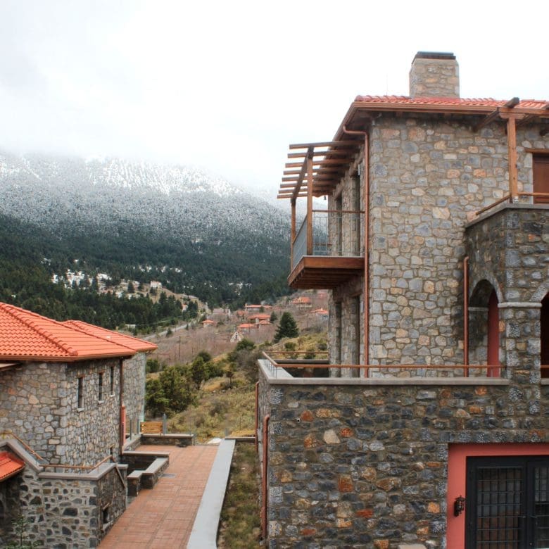 Stone-built hotel exterior with red roof and misty mountain view, Kardaras, Mount Mainalo, Arcadia, Greece