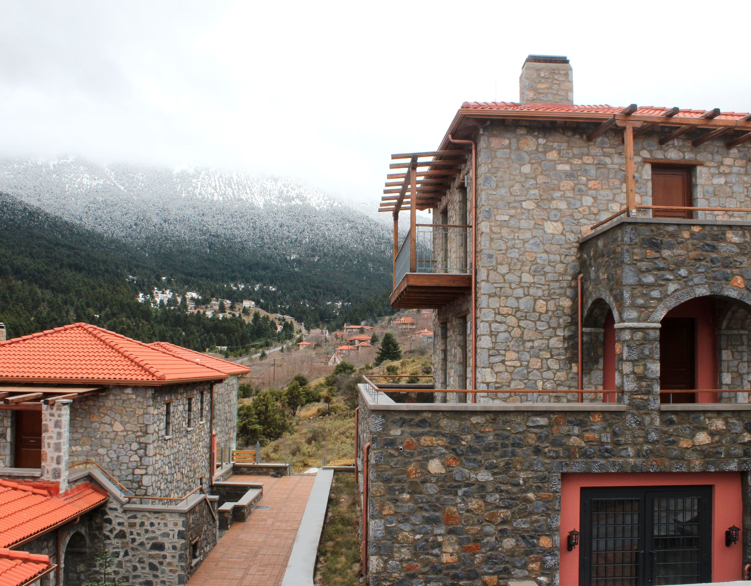 Stone-built hotel exterior with red roof and misty mountain view, Kardaras, Mount Mainalo, Arcadia, Greece