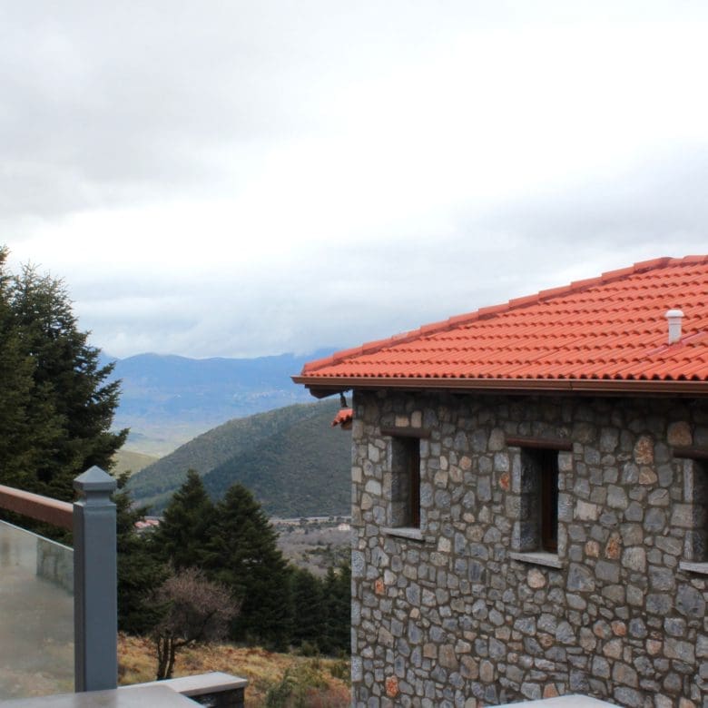 Stone-built hotel exterior with red-tiled roof and mountain backdrop, Kardaras, Mount Mainalo, Arcadia, Greece