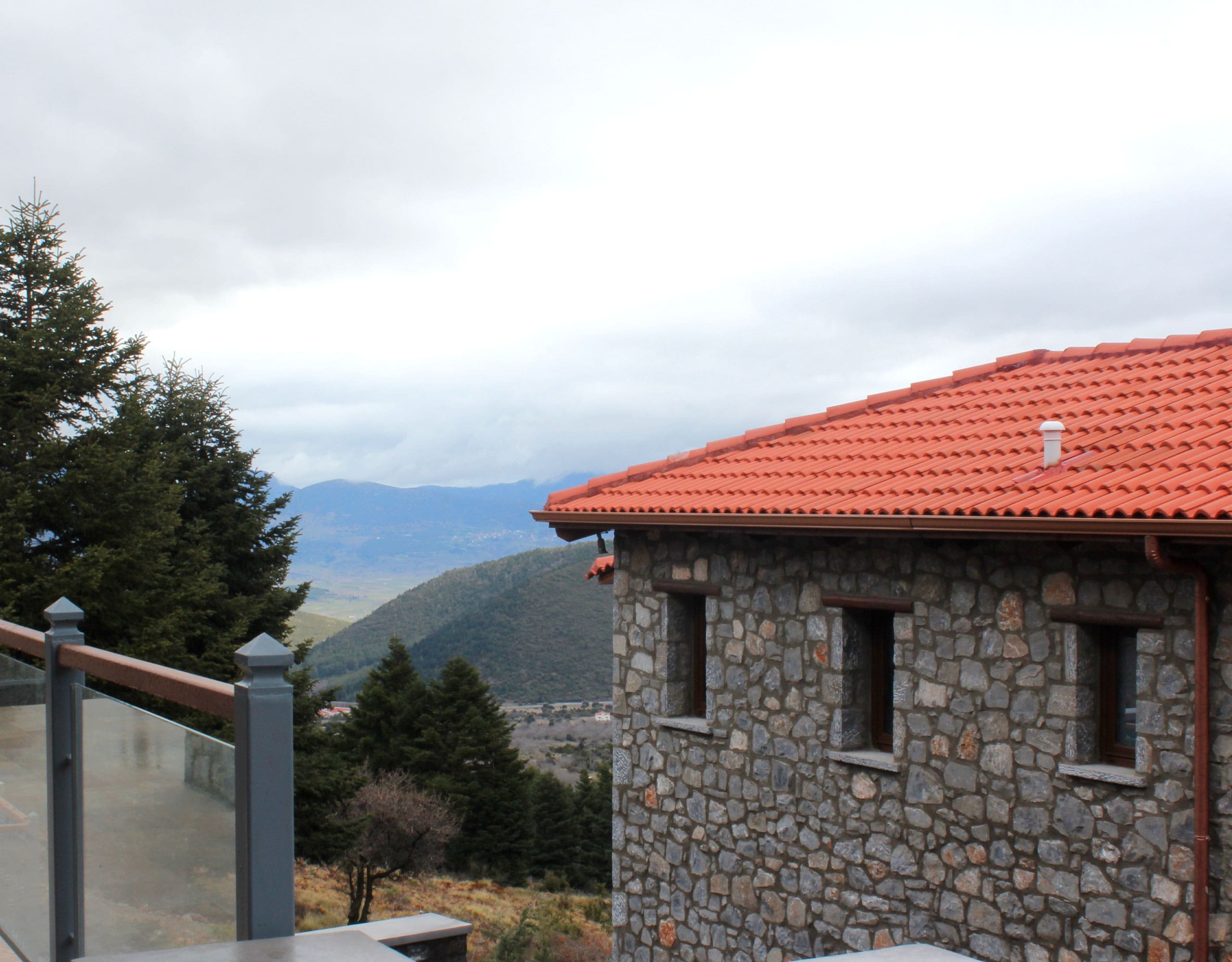 Stone-built hotel exterior with red-tiled roof and mountain backdrop, Kardaras, Mount Mainalo, Arcadia, Greece