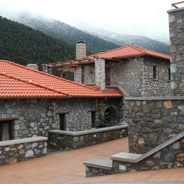 View across stone buildings with red-tiled roofs and forested mountain slopes, Kardaras, Mount Mainalo, Arcadia, Greece