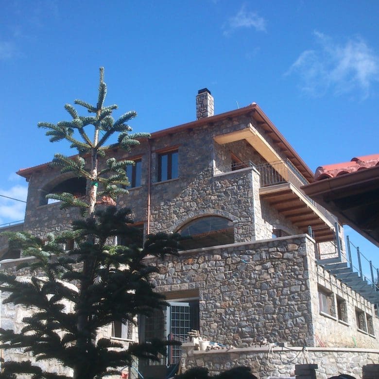 Stone-built hotel exterior with red-tiled roofs and blue sky, Kardaras, Mount Mainalo, Arcadia, Greece