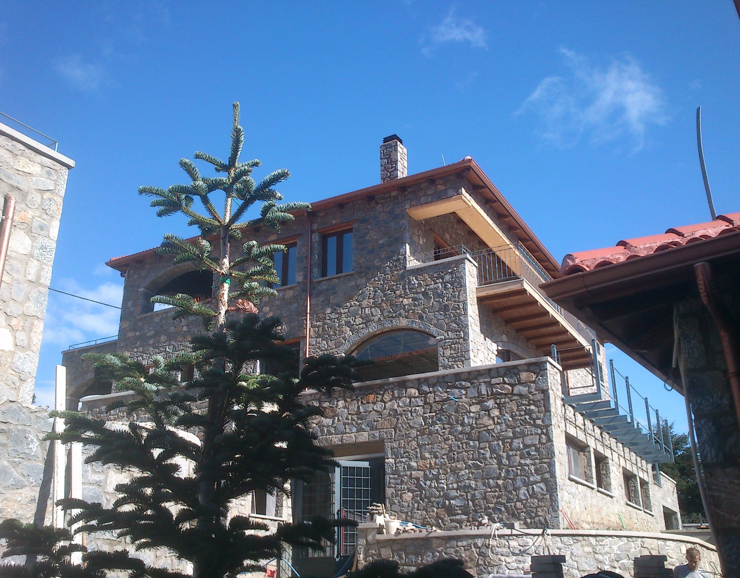 Stone-built hotel exterior with red-tiled roofs and blue sky, Kardaras, Mount Mainalo, Arcadia, Greece