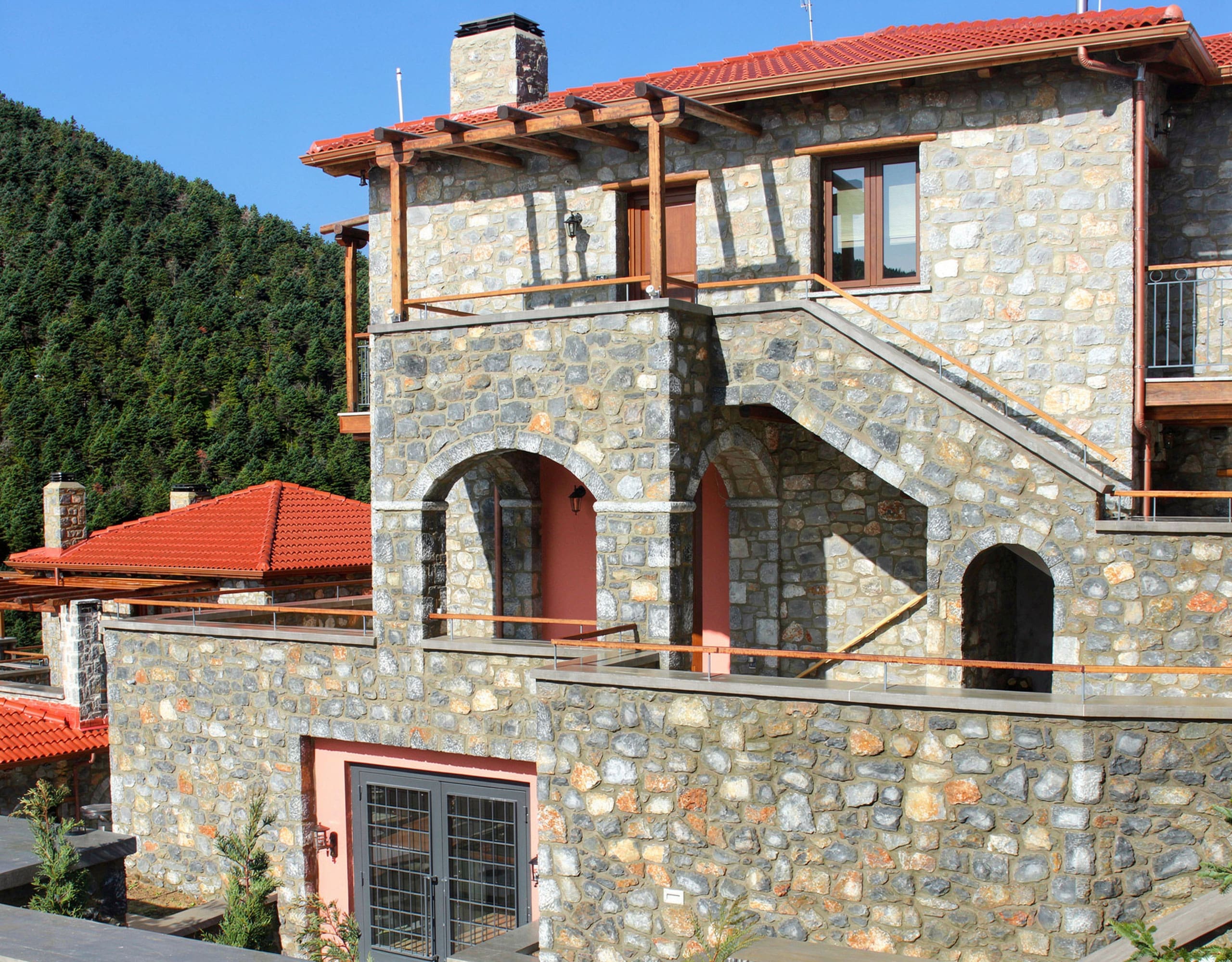 Stone-built hotel facade with arched balcony and red-tiled roof, Kardaras, Mount Mainalo, Arcadia, Greece