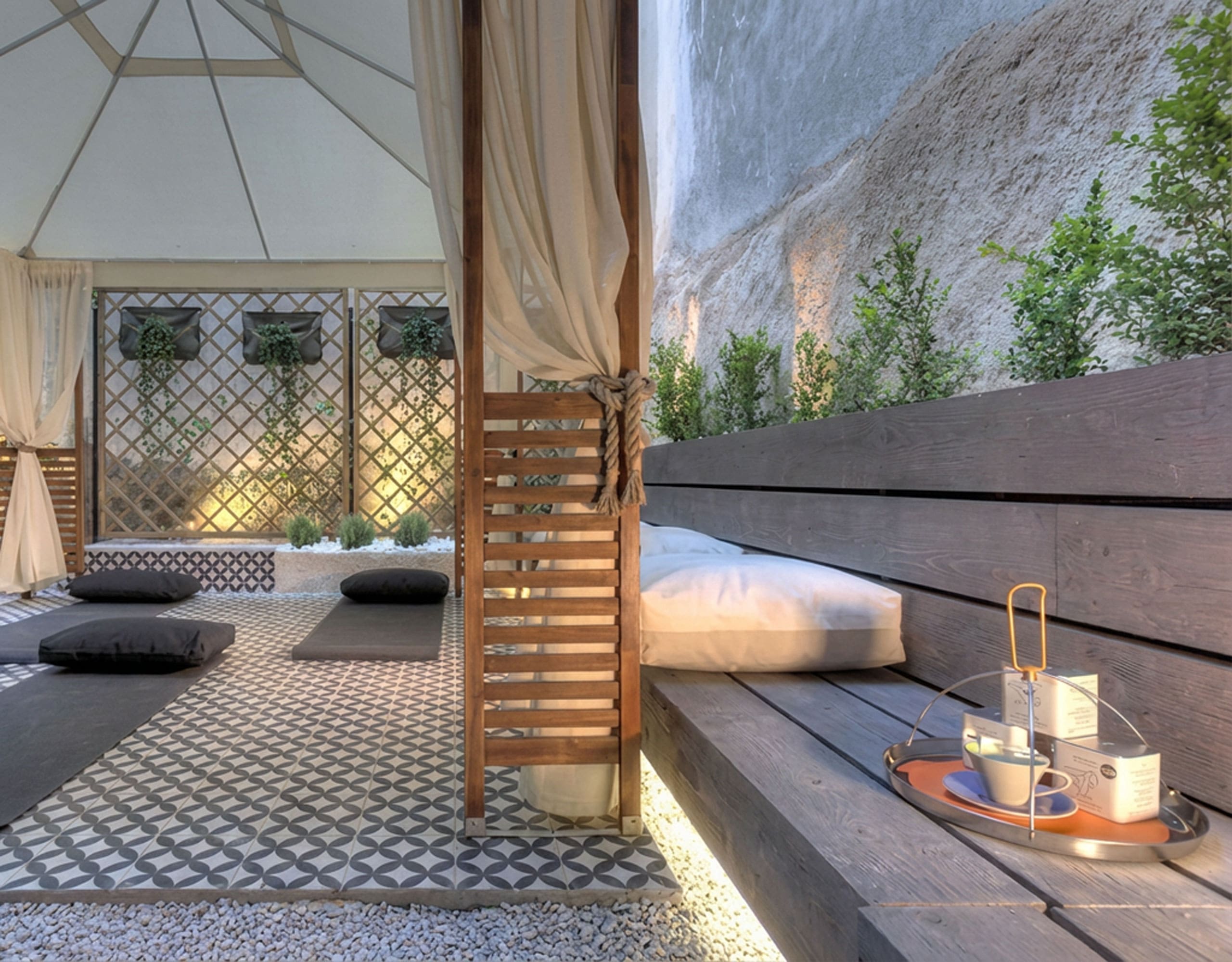 Outdoor courtyard lounge with daybeds, privacy screens, and soft evening lighting, Pasalimani (Zea Marina), Piraeus, Greece