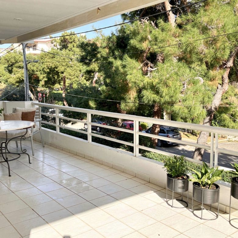 Covered balcony with outdoor dining table, railing, and greenery views, Voula, Athens Riviera, Greece