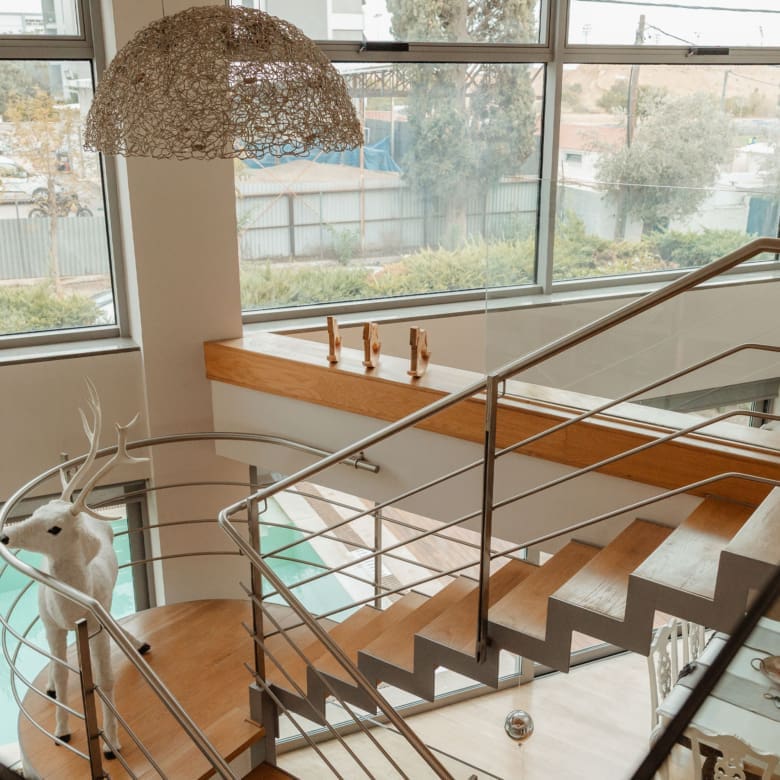 Interior staircase with large window and pendant lighting at a private villa in Alimos, Athens Riviera