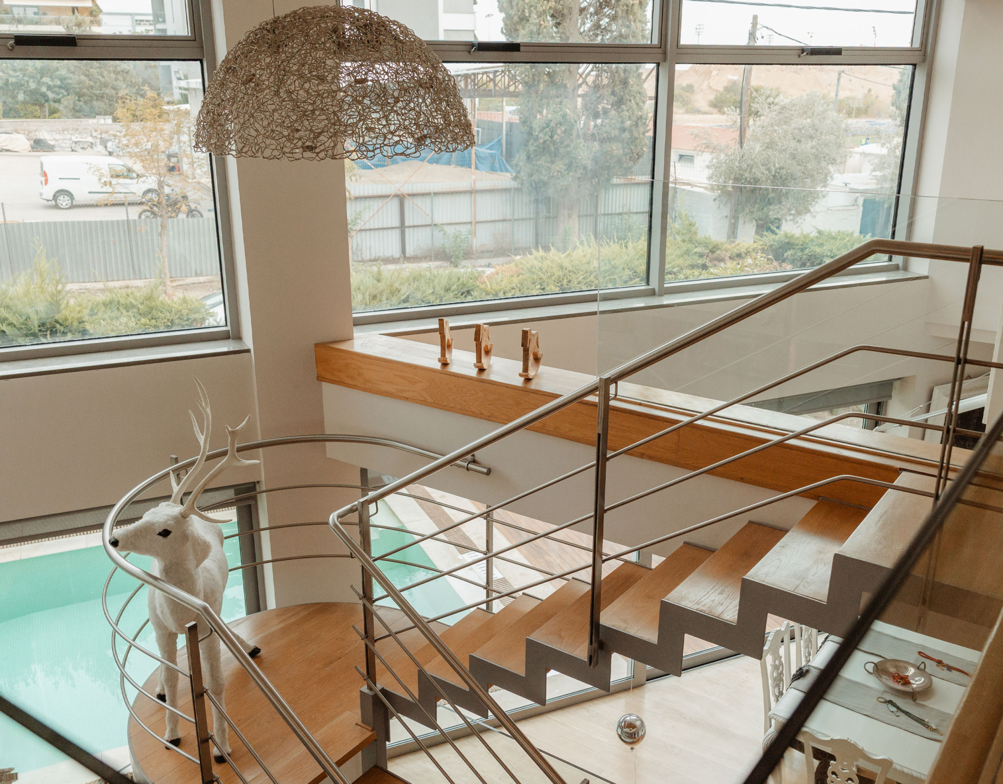 Interior staircase with large window and pendant lighting at a private villa in Alimos, Athens Riviera