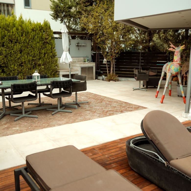 Ground-level outdoor patio with dining area beside the pool at a private villa in Alimos, Athens Riviera