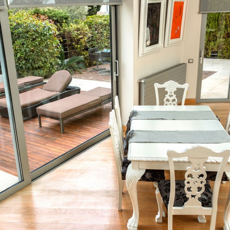 Dining area by sliding doors opening to an outdoor lounge at a private villa in Alimos, Athens Riviera